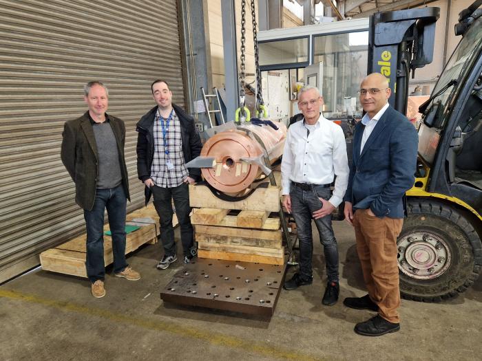 4 men standing with copper cylindrical equipment